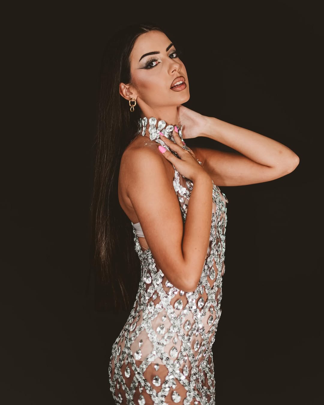 Modelo posando con un vestido brillante en un estudio de fotografía profesional.